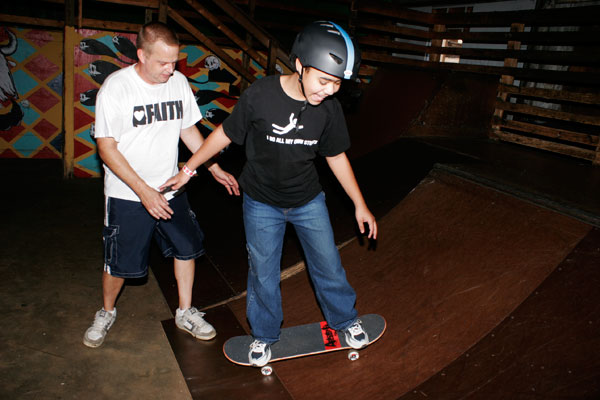 Another A-Skate volunteer helping a kid